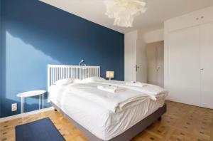 a bedroom with a large white bed and a blue wall at Logement Autour de Moi * * * * * in Chambéry