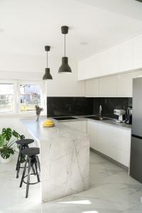 a white kitchen with a marble counter and stools at Lucas apartment in Čapljina