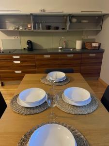 a wooden table with plates and wine glasses on it at Apartmán Pistácia 2 priame centrum BB in Banská Bystrica
