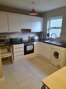 a kitchen with white cabinets and a washing machine at 4 Bleach Green Apartments in Ballycastle