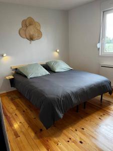 ein großes Bett in einem Schlafzimmer mit Holzboden in der Unterkunft Gîte L’Erable in Haverskerque