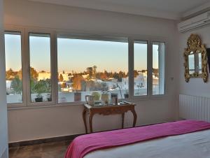 a bedroom with a bed and a table and windows at Dar Souad in La Marsa