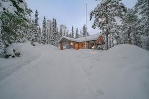 a log cabin in the snow with a snow covered driveway at Koto Lodge - Yllästunturi in Äkäslompolo