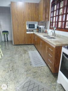 eine Küche mit Holzschränken und einer Mikrowelle in der Unterkunft Chácara dos Pinheiros in São Roque