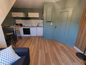 a living room with a blue couch and a kitchen at Le Saint Nicolas in Châteaugiron