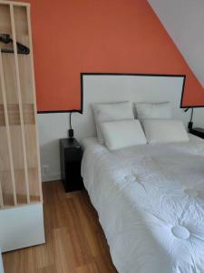 a bedroom with a white bed with an orange wall at Le Saint Nicolas in Châteaugiron