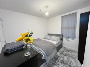 1 dormitorio con 1 cama y un jarrón de flores en un escritorio en Blue Rain 3 en Liverpool