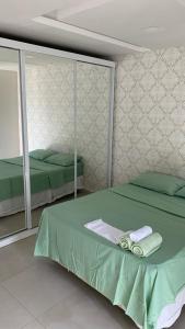 een slaapkamer met 2 bedden, handdoeken en spiegels bij RB hospedagem in Cabo Frio