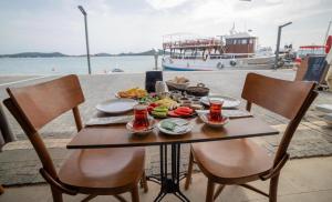 een tafel met eten en een boot in het water bij Mai Otel Cunda in Ayvalık