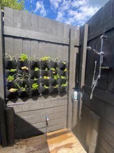 a fence with potted plants on a wall at Kereru Cabin in Palm Beach