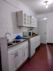 cocina blanca con fregadero y microondas en Casa en el Corazón de San Vicente, en San Vicente de Tagua Tagua