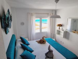 a bedroom with a bed with blue pillows and a window at Casa Puerto Maritimo in Corralejo