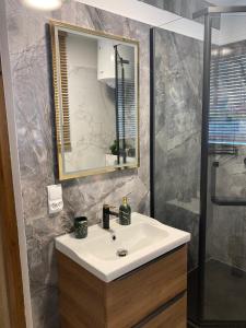 a bathroom with a sink and a mirror and a shower at METRO APARTMENT in Bielsko-Biała