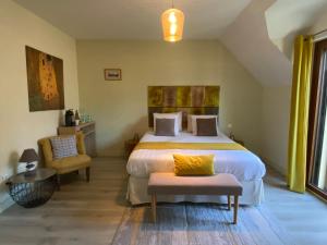 - une chambre avec un grand lit et une chaise dans l'établissement L'Orée du Mont proche du mont saint Michel, à Pontorson