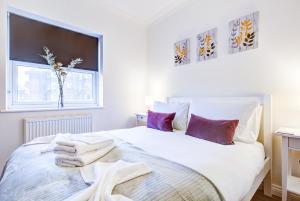 1 dormitorio con 1 cama blanca grande con almohadas moradas en Beautiful Two Bedroom Apartment with Free Parking! en Romford