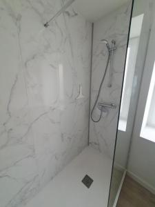 La salle de bains est pourvue d'une douche en marbre blanc. dans l'établissement Location Appartement, à Panissières