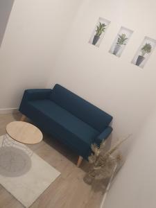 - un canapé bleu dans le salon avec une table dans l'établissement Location Appartement, à Panissières