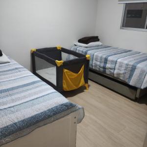 um quarto com duas camas e um cobertor amarelo em Apartamento Lindo e Confortável com 2 quartos e estacionamento grátis Curitiba em Curitiba