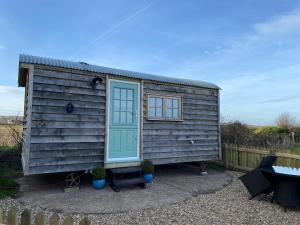 a tiny house with a blue door and a fence at Luxury Shepherd Hut in Kelham
