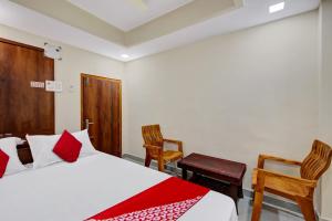 um quarto com uma cama e 2 cadeiras em Super OYO Flagship Hotel Millennia em Visakhapatnam