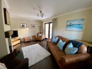 a living room with a brown leather couch and blue pillows at Lapwing Cottage Docking in Docking