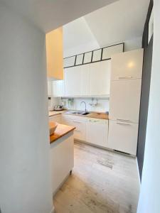 cocina con armarios blancos y suelo de madera en Lovely flat in the heart of the Navigli, en Milán