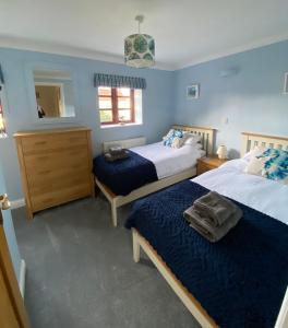 a bedroom with two beds and a mirror at Lapwing Cottage Docking in Docking
