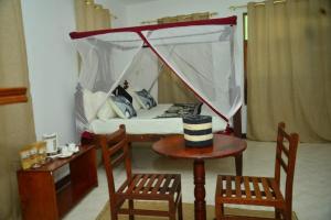 a room with a bed and two chairs and a table at La Neisha Hotel Zanzibar in Stone Town