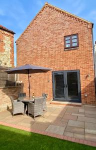 a patio with a table and chairs and an umbrella at Lapwing Cottage Docking in Docking +7 photos