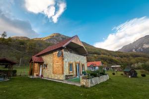 a small house in a field with mountains in the background at Vila Kristina in Andrijevica