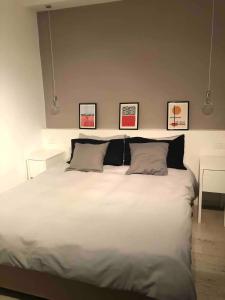 1 dormitorio con 1 cama blanca grande y 3 cuadros en la pared en Lovely flat in the heart of the Navigli, en Milán