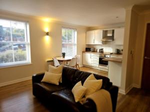 a living room with a black couch and a kitchen at Eaglegate in Colchester