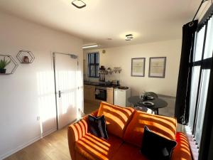a living room with a orange couch and a kitchen at Rooms Near Me - Apartment 3, Smart Tv, Free Parking in Halesowen