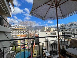 a balcony with an umbrella and chairs and buildings at Chic & Comfort Homes in Central Volos # 3 in Volos