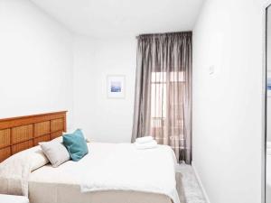 a white bedroom with a bed and a window at Alojamientos Fenix in Murcia