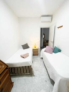 two beds in a room with white walls at Alojamientos Fenix in Murcia