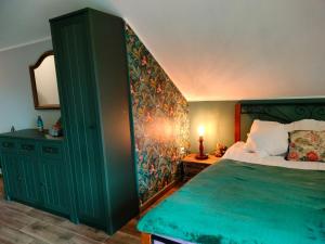 een slaapkamer met een groen bed en een spiegel bij Izerska Zagroda in Świeradów-Zdrój