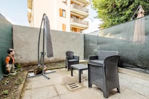 een patio met stoelen en een parasol naast een hek bij A.P. Appartamento o camera in Corsico