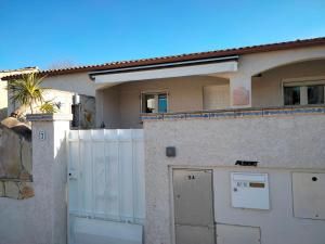a house with a white fence and a gate at Maison 4 à 6 pers Quartier calme Tout confort in Aigues-Mortes