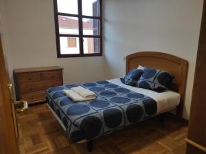 1 dormitorio con cama con sábanas azules y ventana en Dúplex Parque Europa II, en Ezcaray