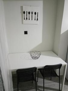 a white table with two chairs and knives on a wall at Cocomelo Apts 2 in Heraklio