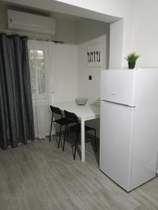 una cucina con tavolo e frigorifero bianco di Cocomelo Apts 2 a Heraklion