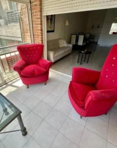 sala de estar con 2 sillas rojas y sofá en Lacroze Departamento Buenos Aires en Buenos Aires