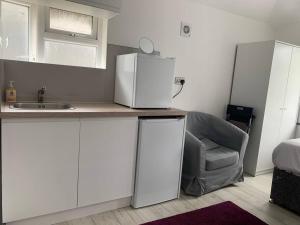 a kitchen with a sink and a refrigerator and a chair at Modern Brand New Build STUDIO Apartments LONDON in London