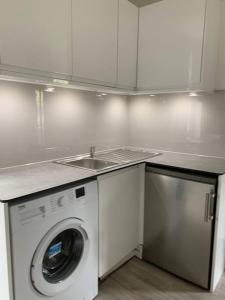 a kitchen with a washing machine and a sink at Modern Brand New Build STUDIO Apartments LONDON in London