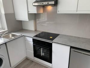 una cocina con armarios blancos y horno negro en Modern Brand New Build STUDIO Apartments LONDON, en Londres