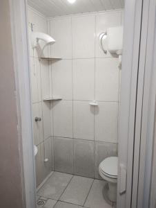 y baño blanco con ducha y aseo. en Aluguéis Cleusa, en Torres