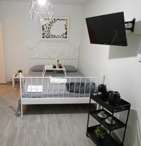 1 dormitorio con cuna blanca y TV en la pared en Cocomelo Apts 2, en Heraclión