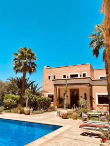 a house with a swimming pool and palm trees at La Villa Des Golfs & PinkCactus in Marrakesh