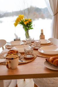 una mesa con platos y tazas y un jarrón de flores en Pod Kalwarią, 